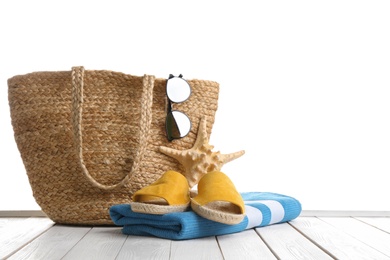 Photo of Stylish bag with beach accessories on white wooden table. Space for text