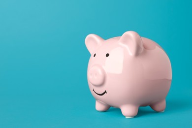 Photo of Ceramic piggy bank on turquoise background. Space for text