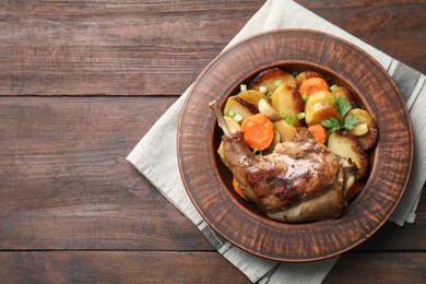 Photo of Tasty cooked rabbit meat with vegetables on wooden table, top view. Space for text