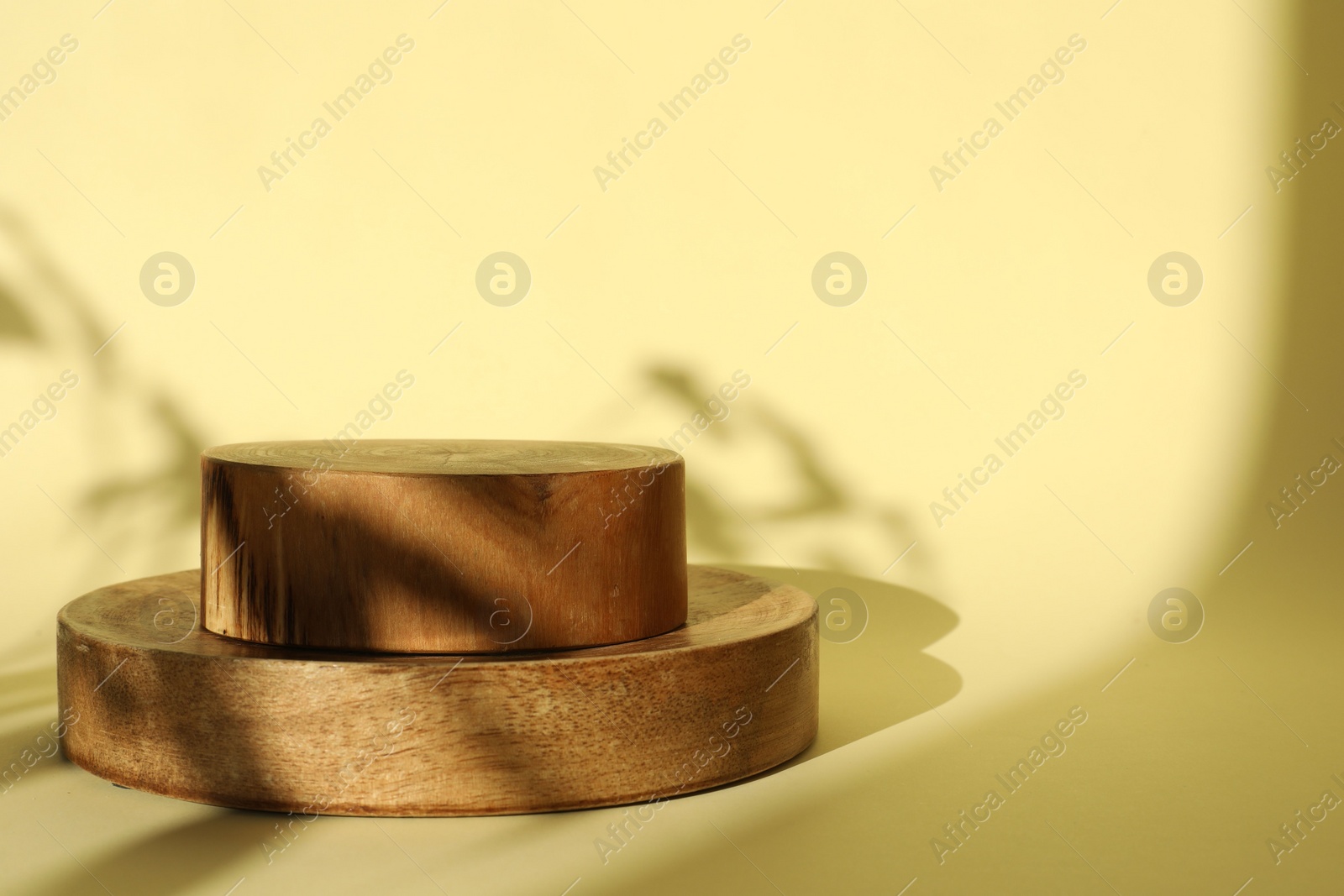 Photo of Presentation of product. Wooden podiums on yellow background. Space for text