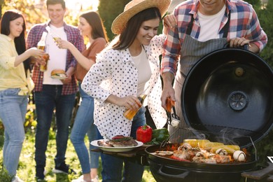 People with drinks having barbecue party outdoors