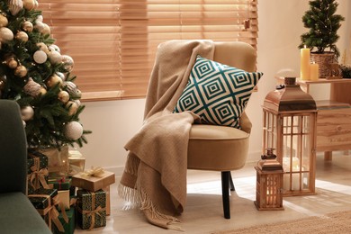 Armchair near Christmas tree and gift boxes in room