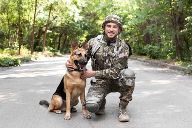 Man in military uniform with German shepherd dog outdoors