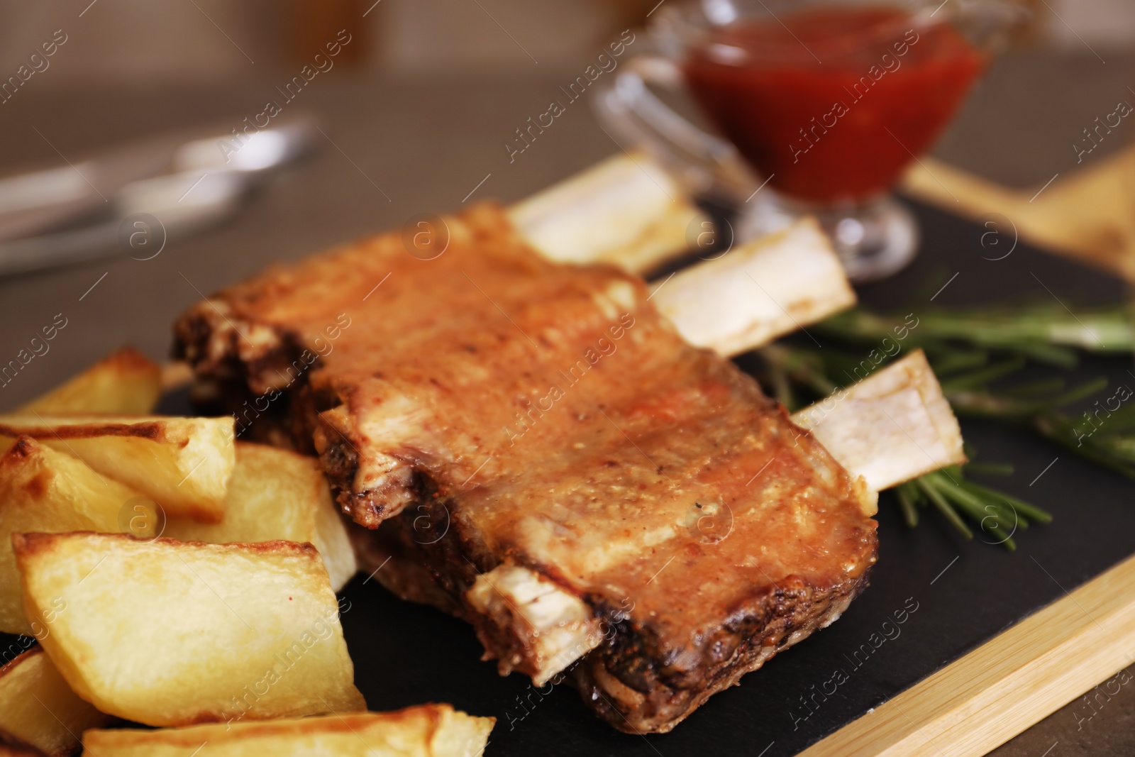 Photo of Fried ribs served with garnish on board, closeup. Delicious meat