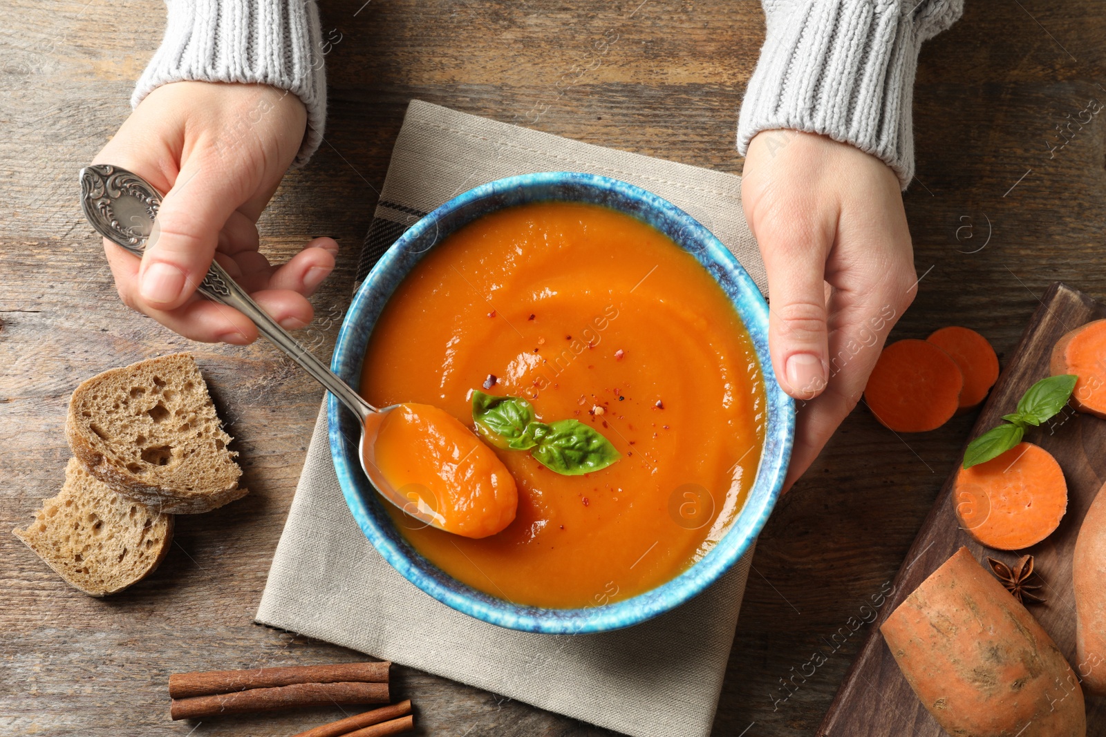 Photo of Woman eating sweet potato soup at table, top view