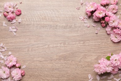Photo of Beautiful sakura tree blossoms on wooden background, flat lay. Space for text