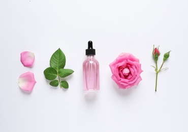 Photo of Composition with rose essential oil and flowers on white background, top view