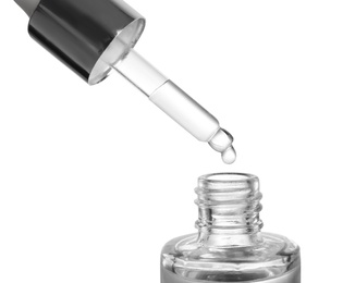 Dripping essential oil from pipette into glass bottle on white background