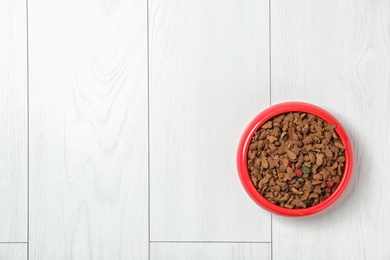 Bowl with food for cat or dog on wooden background. Pet care