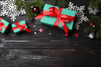 Flat lay composition with Christmas gift boxes on black wooden table. Space for text