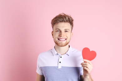 Photo of Portrait of young man with paper heart on color background