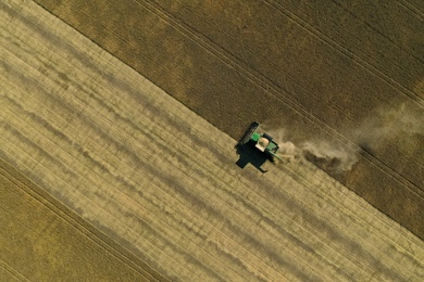 Beautiful aerial view of modern combine harvester working in field on sunny day. Agriculture industry