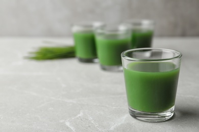 Photo of Glass of wheat grass juice on marble table. Space for text