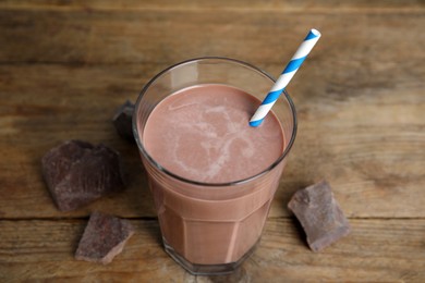 Photo of Delicious chocolate milk in glass on wooden table