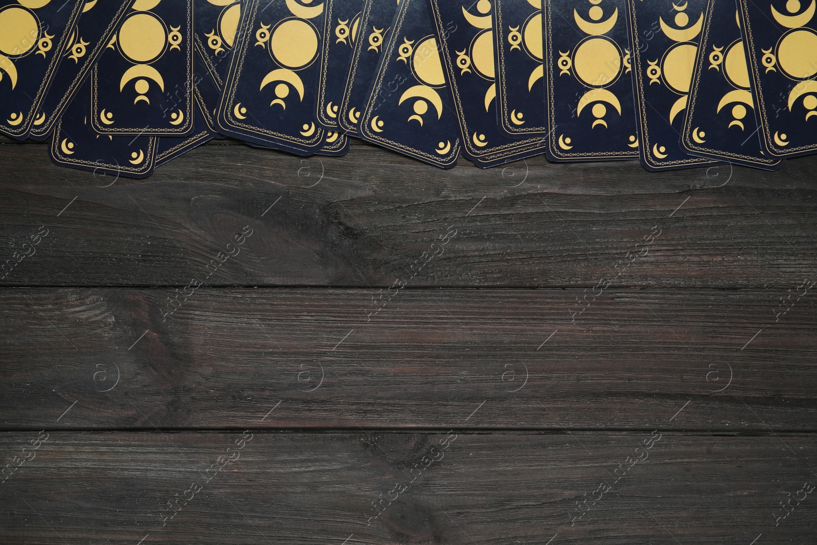 Photo of Tarot cards on black wooden table, flat lay with space for text. Reverse side