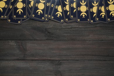 Photo of Tarot cards on black wooden table, flat lay with space for text. Reverse side