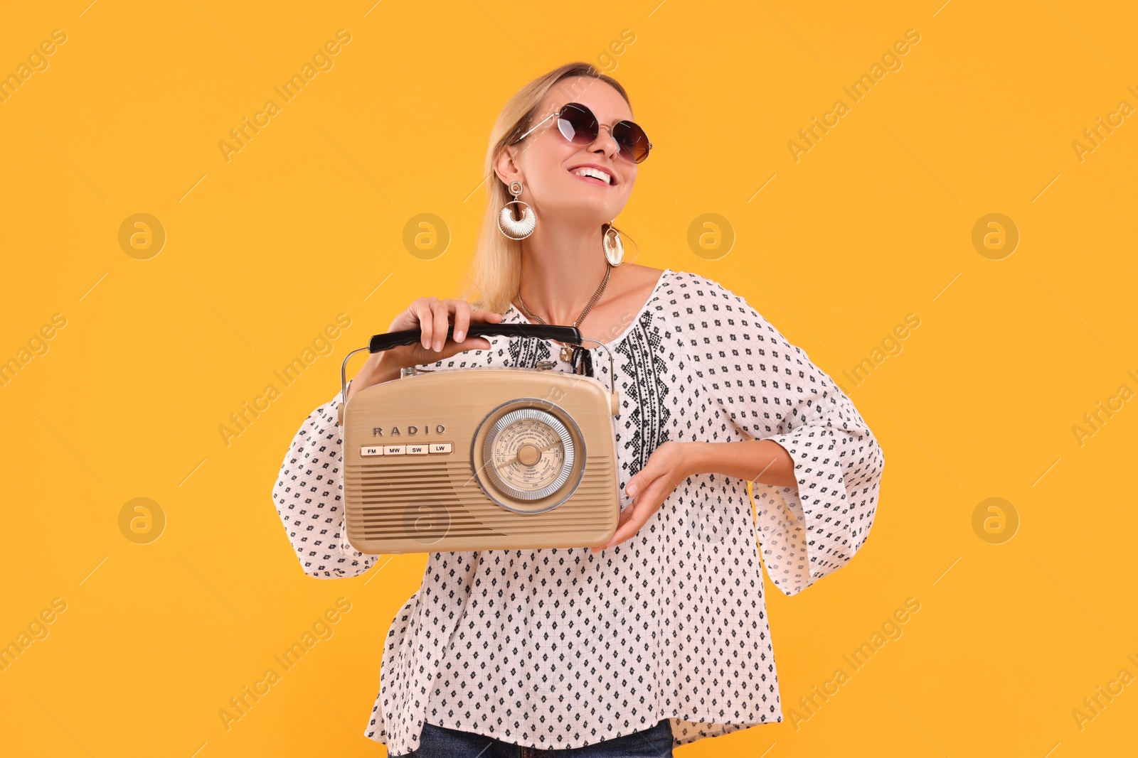 Photo of Portrait of happy hippie woman with retro radio receiver on yellow background