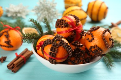 Pomander balls made of fresh tangerines and cloves on light blue wooden table