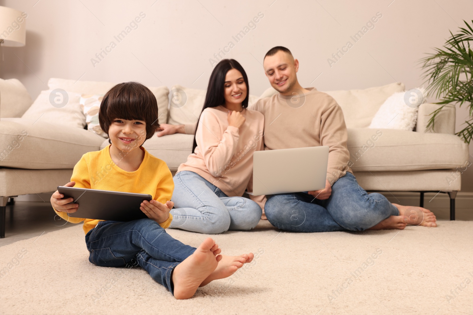 Photo of Happy family with gadgets on floor at home