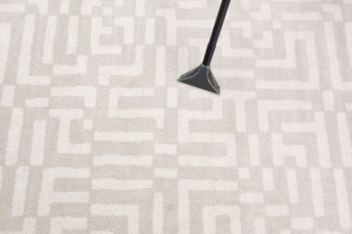 Removing dirt from carpet with vacuum cleaner indoors, closeup. Space for text