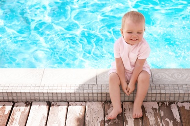 Photo of Little baby sitting near outdoor swimming pool. Dangerous situation