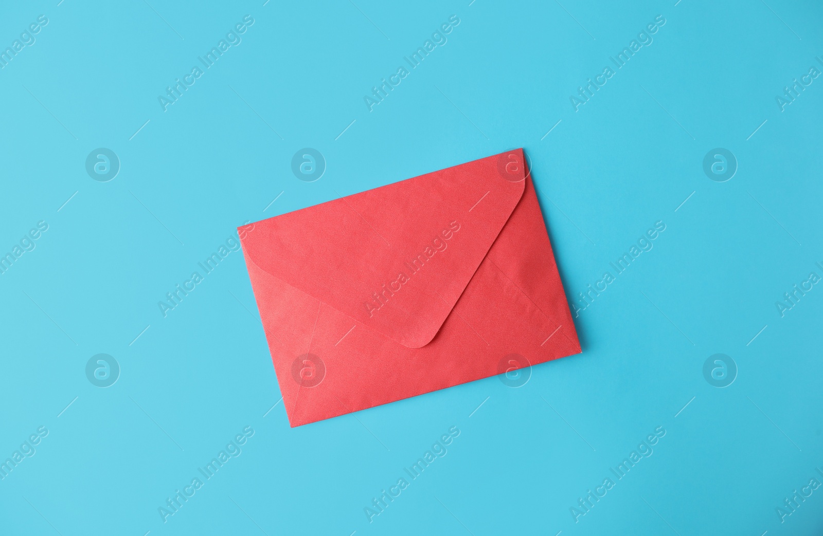 Photo of Red paper envelope on light blue background, top view