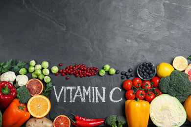 Photo of Phrase VITAMIN C and different products on black table, flat lay. Space for text