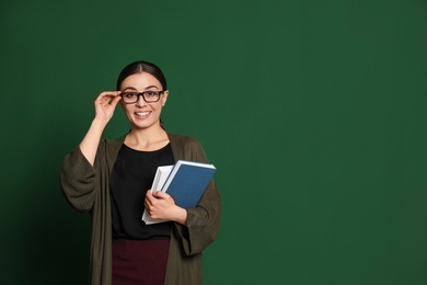 Photo of Portrait of young teacher with books on green background. Space for text