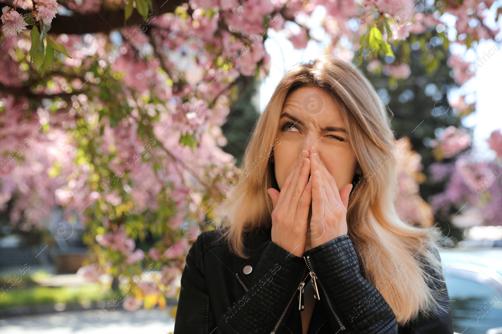 Photo of Woman suffering from seasonal pollen allergy near blossoming tree outdoors