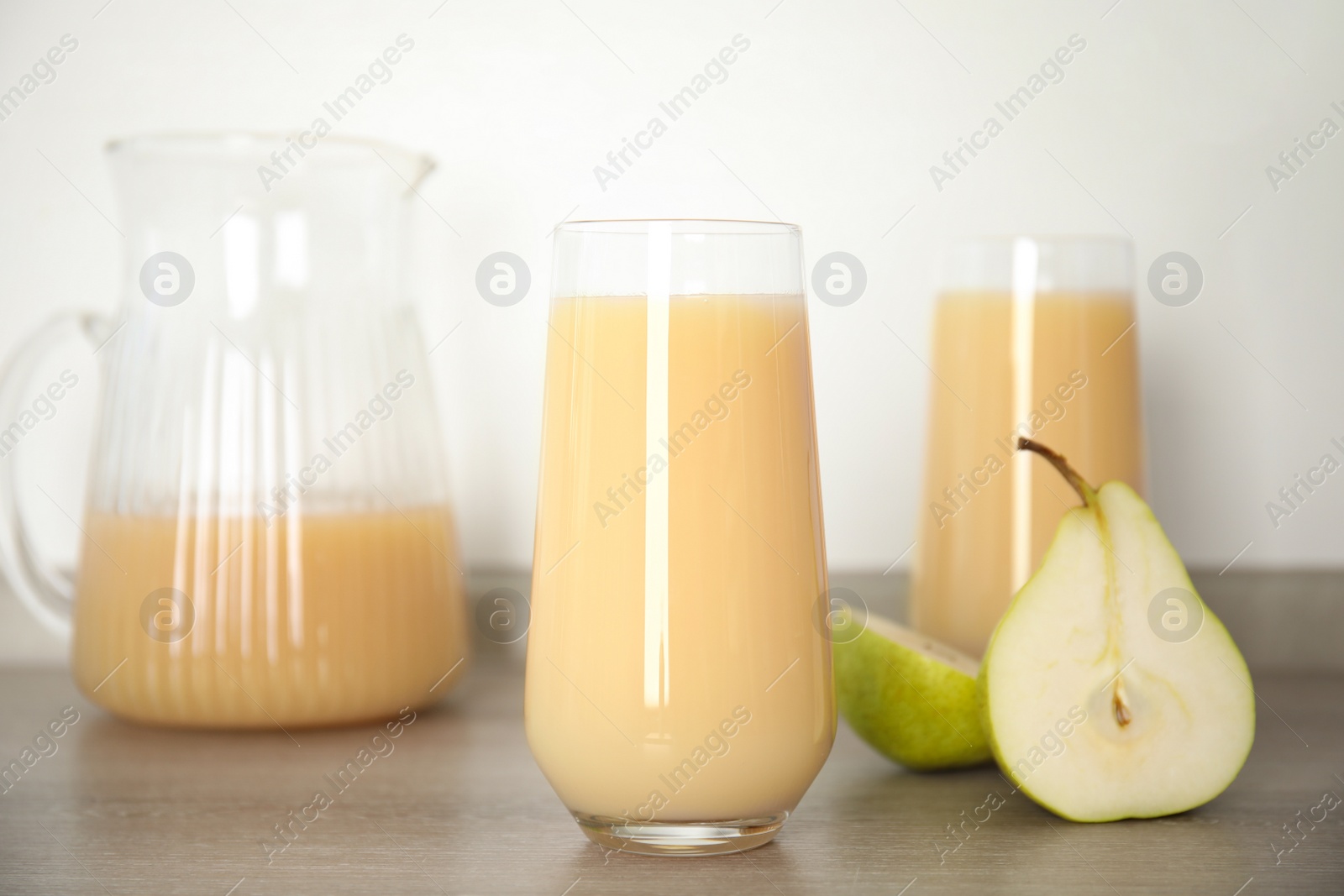 Photo of Tasty pear juice and cut fruit on wooden table, closeup