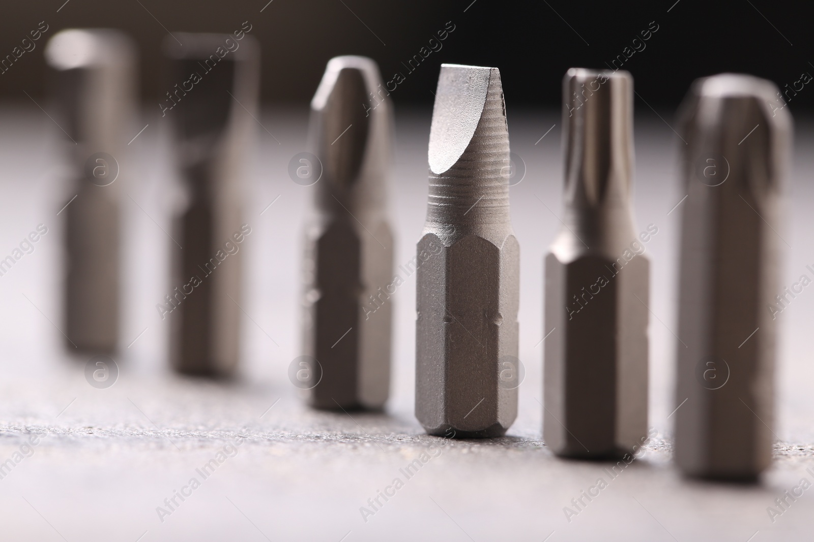 Photo of Different screwdriver bits on grey table, closeup