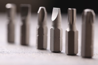 Photo of Different screwdriver bits on grey table, closeup