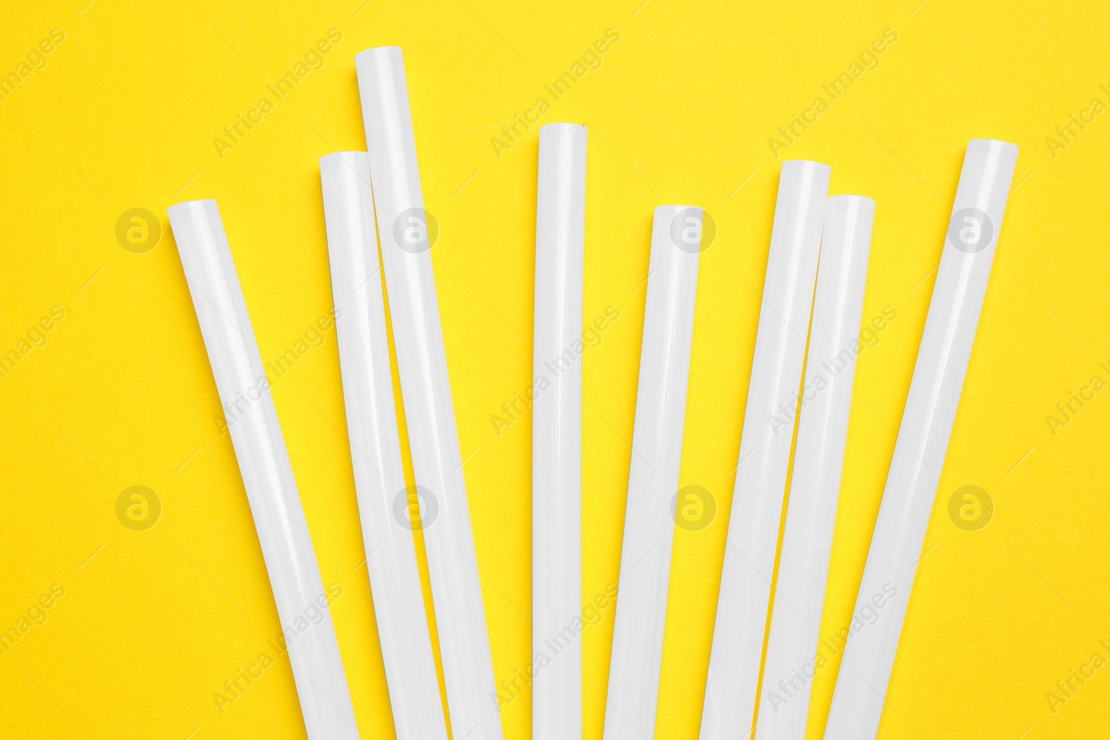 Photo of Many glue gun on yellow background, flat lay