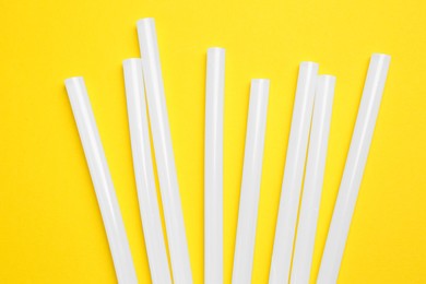 Photo of Many glue gun on yellow background, flat lay