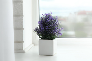 Photo of Beautiful artificial plant in flower pot on window sill