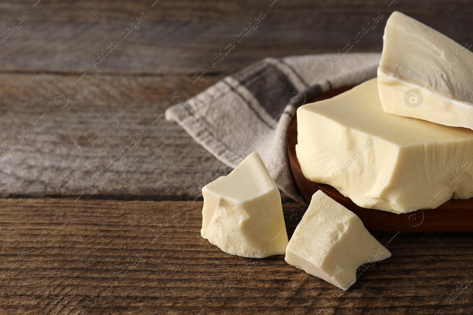 Photo of Pieces of tasty white chocolate on wooden table, closeup. Space for text