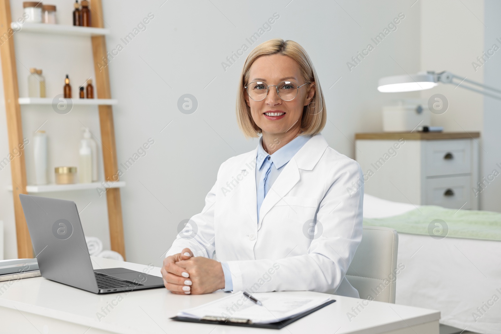 Photo of Portrait of happy dermatologist at white table in clinic