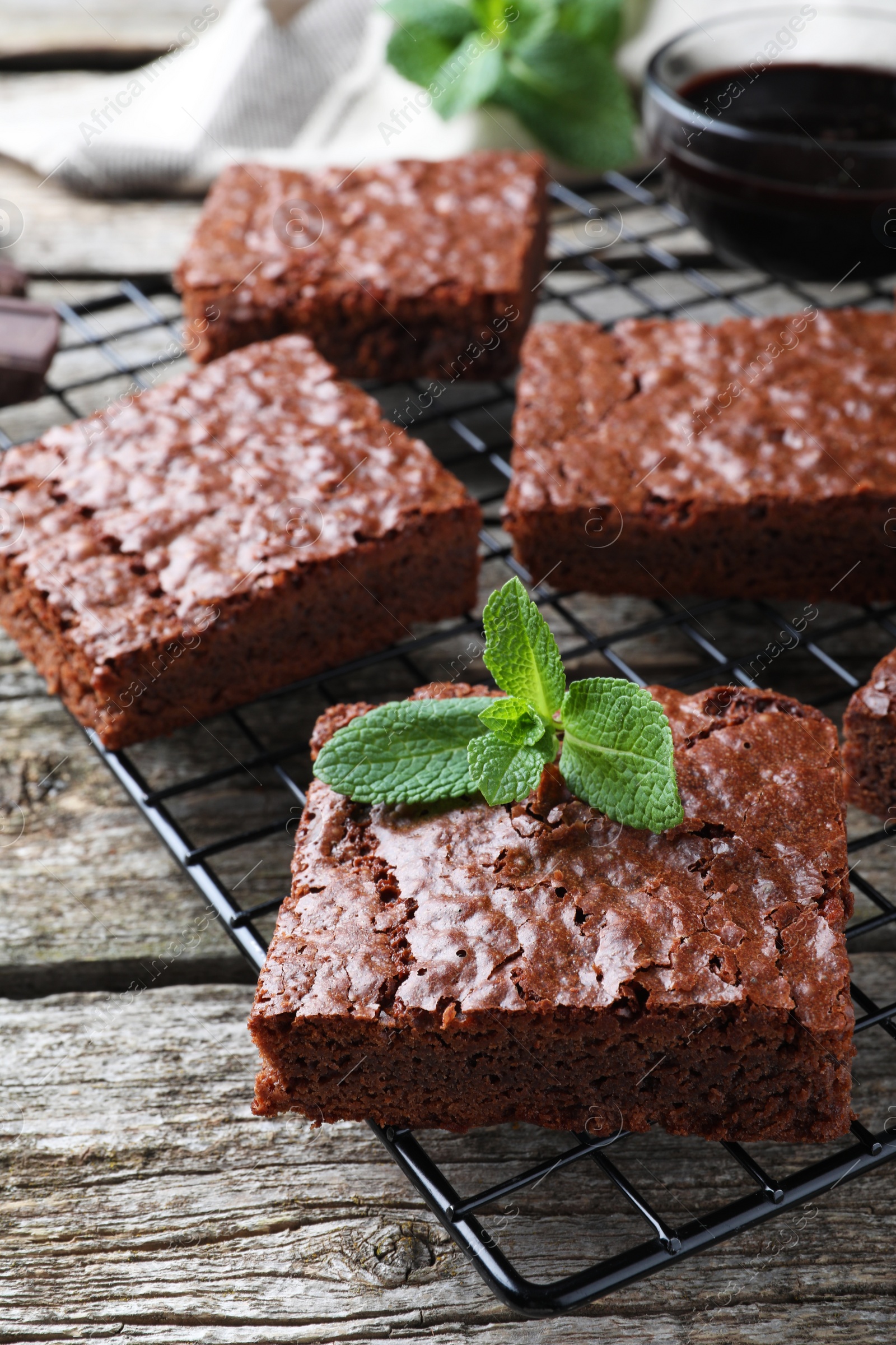 Photo of Cooling rack with delicious chocolate brownies and fresh mint on wooden table, closeup