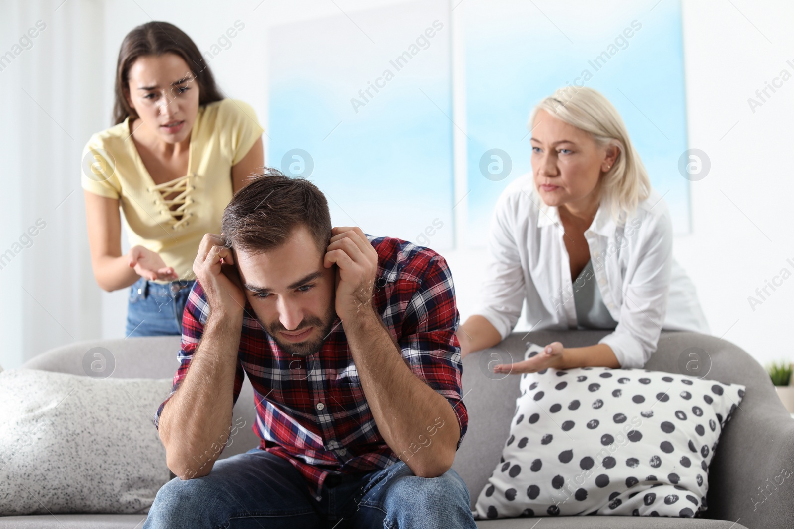 Photo of Young man having argument with wife and mother-in-law at home. Family quarrel