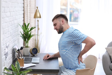 Young man suffering from back pain in office