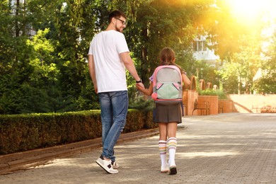 Image of Father taking his daughter to school, back view