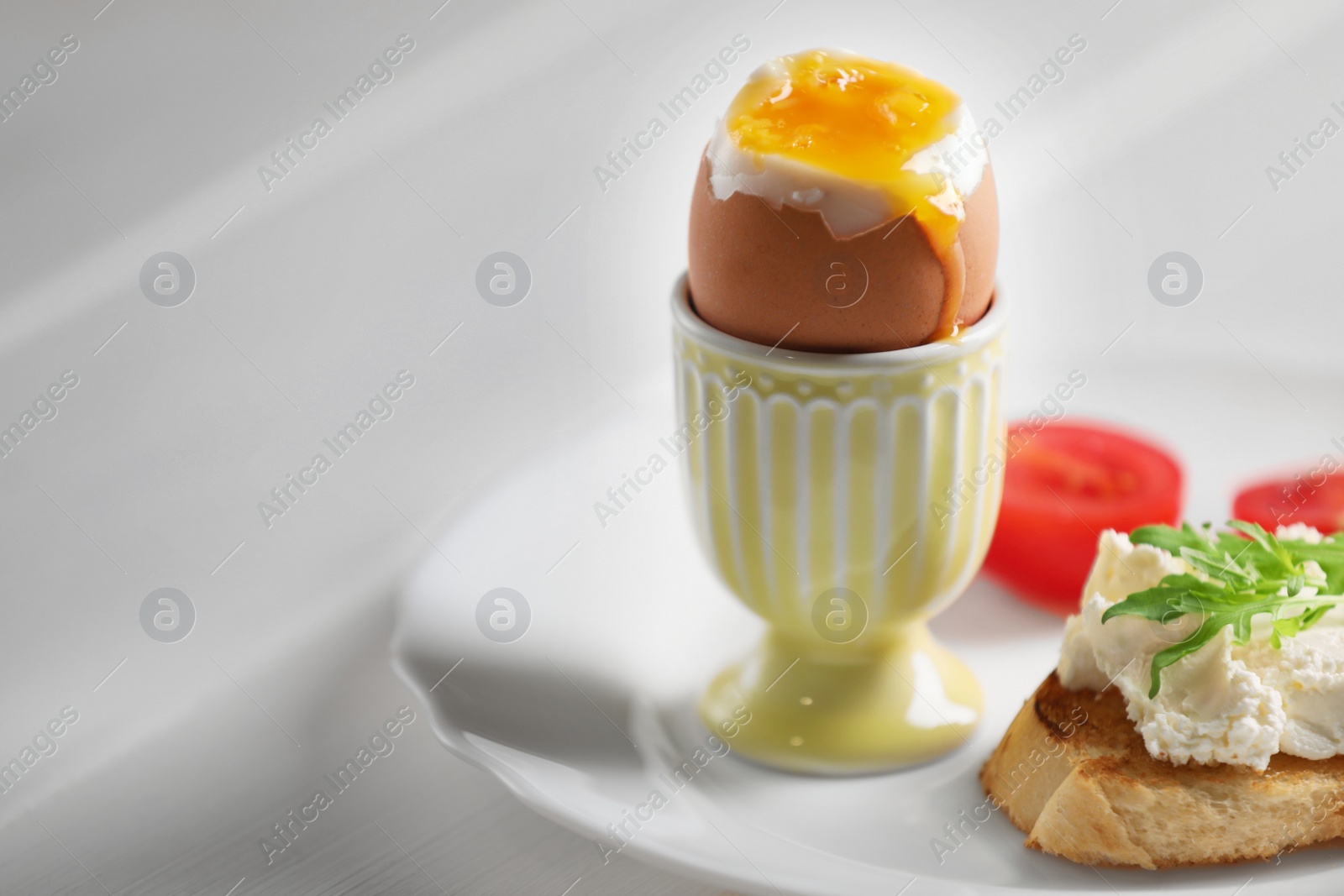 Photo of Fresh soft boiled egg in cup and sandwich on white wooden table. Space for text