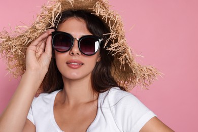 Photo of Beautiful woman with stylish straw hat and sunglasses on pink background