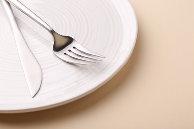 Photo of Setting with stylish cutlery on beige table, closeup. Space for text
