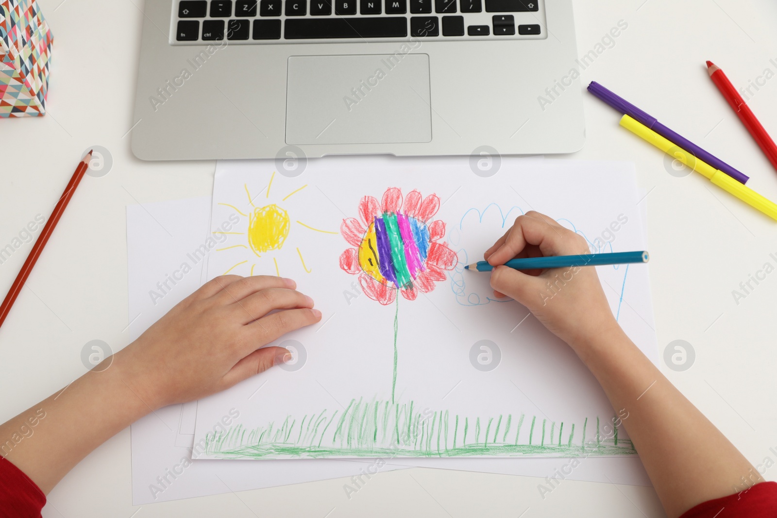 Photo of Little girl drawing on paper with pencil at online lesson indoors, above view. Distance learning