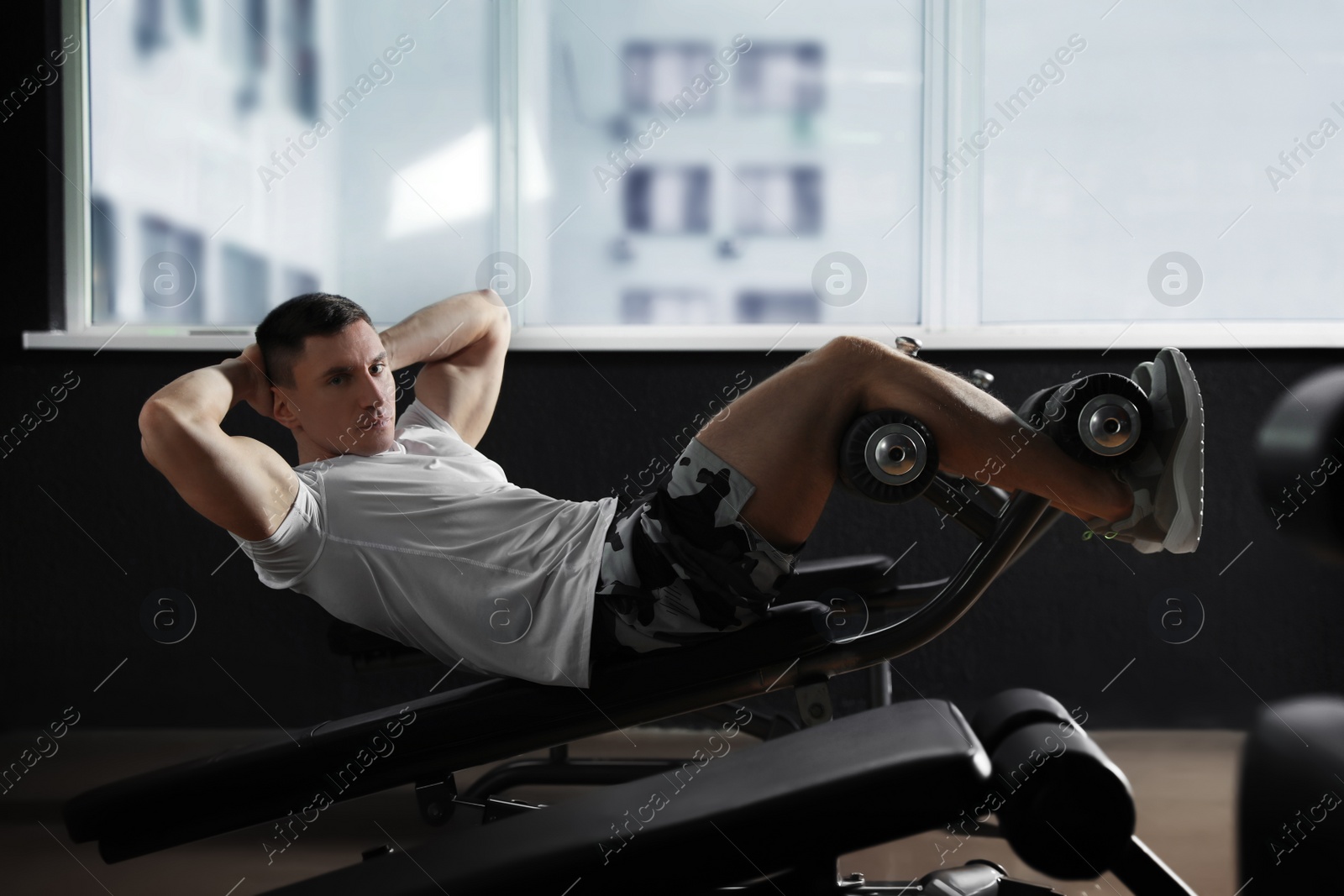 Photo of Man working out on adjustable sit up bench in modern gym