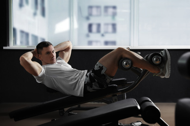 Man working out on adjustable sit up bench in modern gym