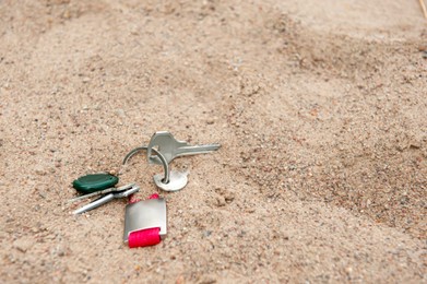 Photo of Keys on sand, space for text. Lost and found
