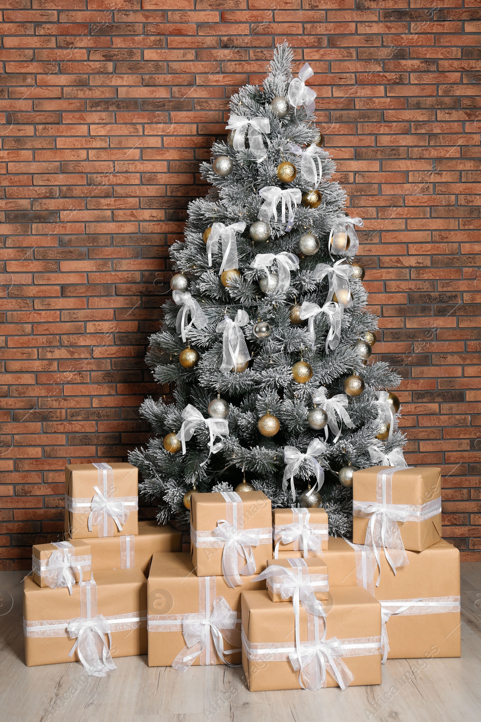 Photo of Decorated Christmas tree and gift boxes near brick wall