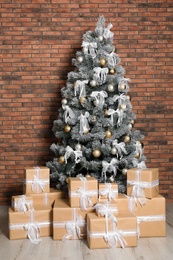 Decorated Christmas tree and gift boxes near brick wall